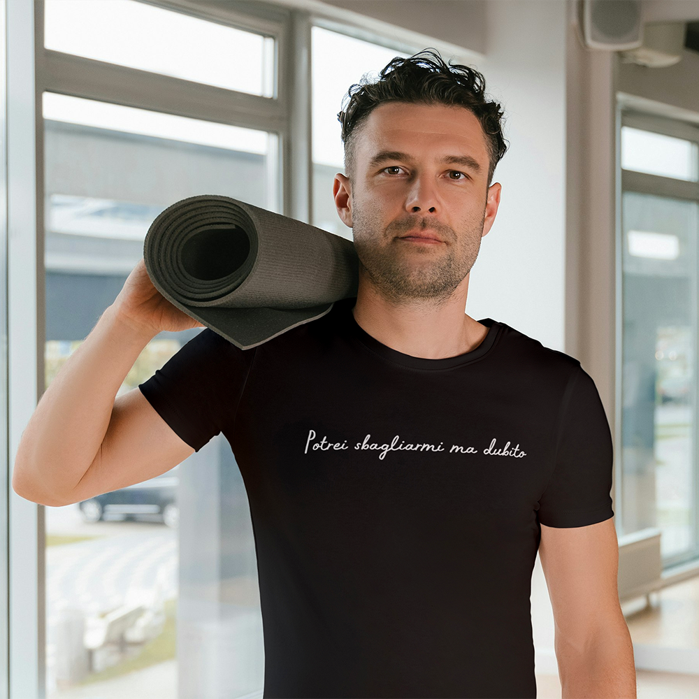 Due T-shirt Dubito Uomo de Il mio negozio, una bianca e una nera con la scritta "Potrei sbagliarmi ma dubito" in corsivo, appese a grucce di legno sotto un'edera verde. Magliette personalizzate divertenti, su sfondo bianco.