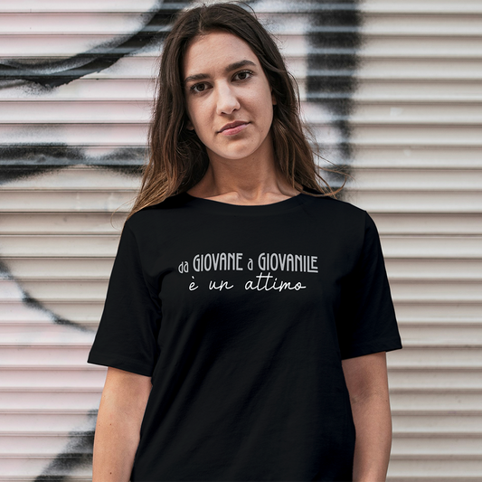 Una donna dai lunghi capelli castani indossa la T-shirt Giovane de Il mio negozio, una maglietta nera personalizzabile con la scritta "da GIOVANE a GIOVANILE è un attimo" in grassetto bianco.