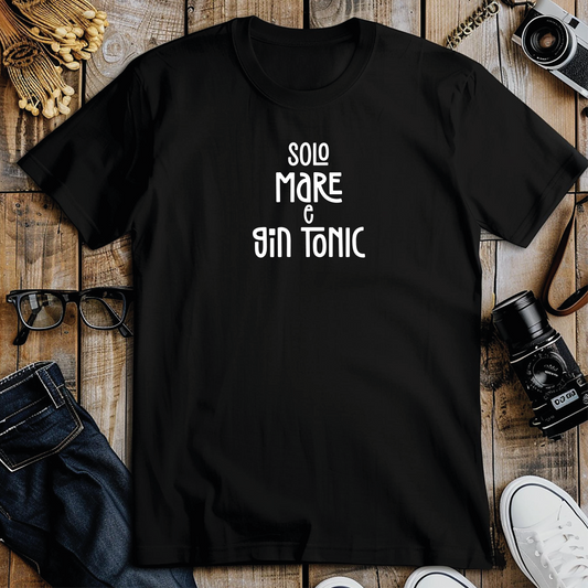 La T-shirt Mare e GinTonic de Il mio negozio, bianca con scritta rosa "SOLO MARE & GIN TONIC", è caratterizzata da maniche arrotolate e orlo annodato, perfetta per chi ama le magliette personalizzate divertenti. Accanto a un cappello intrecciato su sfondo chiaro.