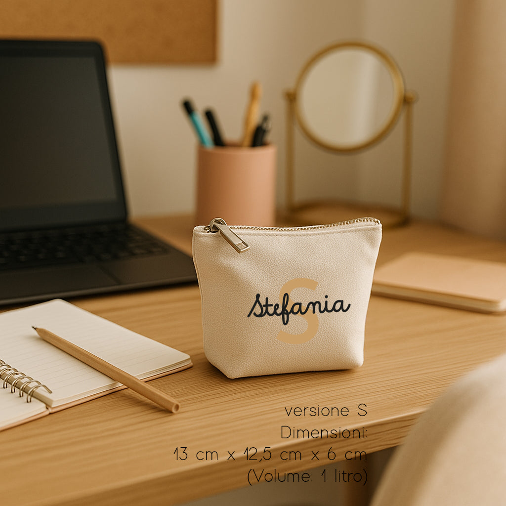 Pochette piccola in cotone canvas naturale personalizzata con iniziale e nome, fotografata su scrivania in ambientazione minimal.