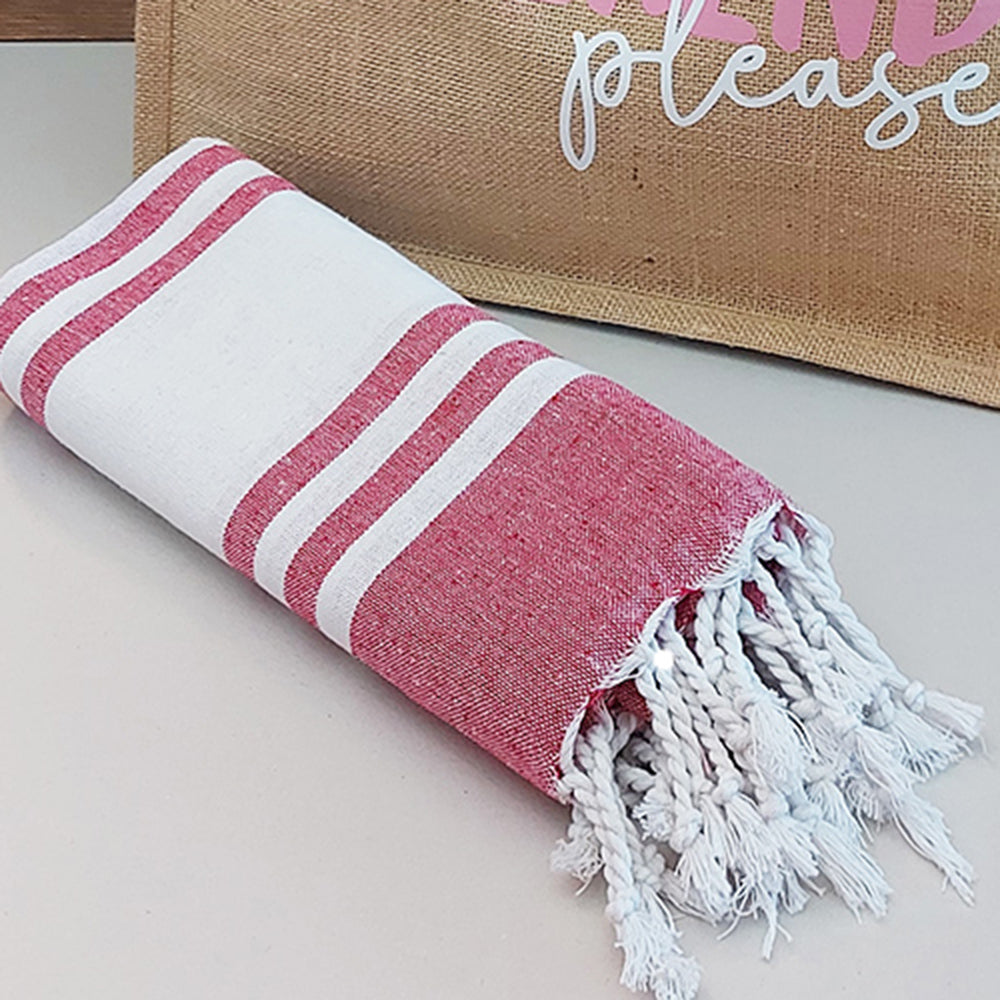 Il Combo Borsa Juta e Telo Fouta WEEKEND di In Casa di Ale è composto da una borsa in juta color tan con la scritta "WEEKEND please" in rosa/bianco e da un asciugamano fouta a righe rosse, ideale per le fughe estive del 2025.