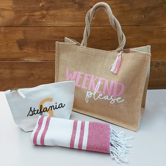 Il Combo Borsa Juta, Telo Fouta e Pochette di Casa di Ale presenta una borsa in juta con testo in italiano e scritte in blu, un sacchetto con zip Stefania bianco con una S arancione e un Telo Fouta a righe, il tutto su una superficie chiara con uno sfondo in legno.