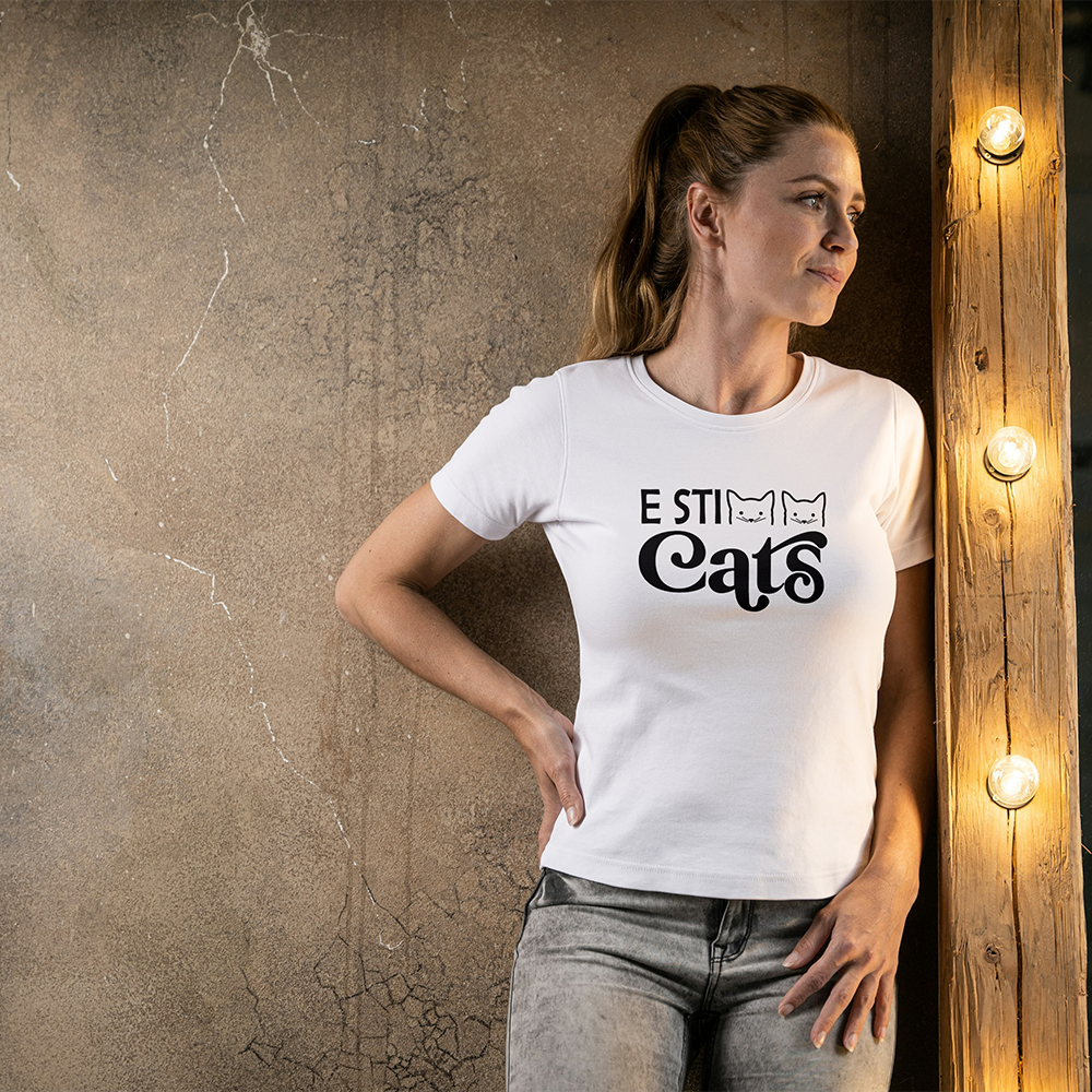 La T-shirt E sticats de Il mio negozio è caratterizzata dal testo nero "E STI Cats" con facce di gatto nel design, perfetto per i fan delle magliette personalizzate divertenti! Da abbinare a sneakers rosa e a un cerchietto nero scintillante con orecchie da Minnie Mouse.