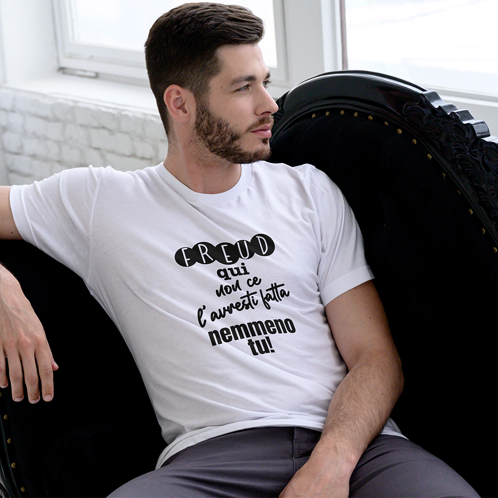 La T-shirt Freud de Il mio negozio è una maglietta bianca ripiegata con il testo italiano "Freud qui non ce l'hai fatta nemmeno tu!" visualizzato su una superficie nera; sullo sfondo compare una tazza rosa con puntini neri, che la rende una perfetta idea regalo.