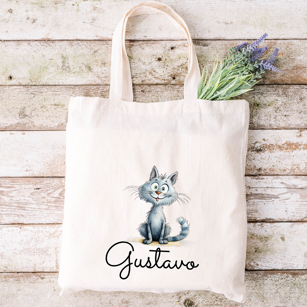 Borsa tote beige con un gatto grigio a fumetti, la scritta "Gustavo" e fiori color lavanda, perfetta da abbinare allo Specchietto Tondo di In Casa di Ale per un look coordinato e affascinante.