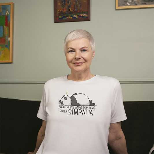 Una donna sorridente con i capelli corti e grigi indossa la T-shirt Simpatia de Il mio negozio, una maglietta bianca con un panda animato e una scritta in italiano.
