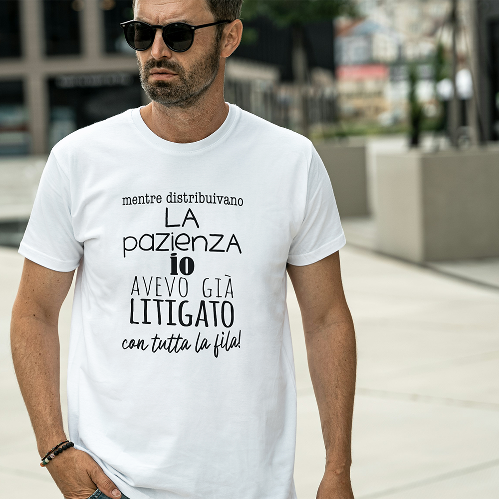 Un uomo con occhiali da sole e una maglietta bianca Pazienza by Il mio negozio con testo in italiano sta all'aperto su un marciapiede della città .