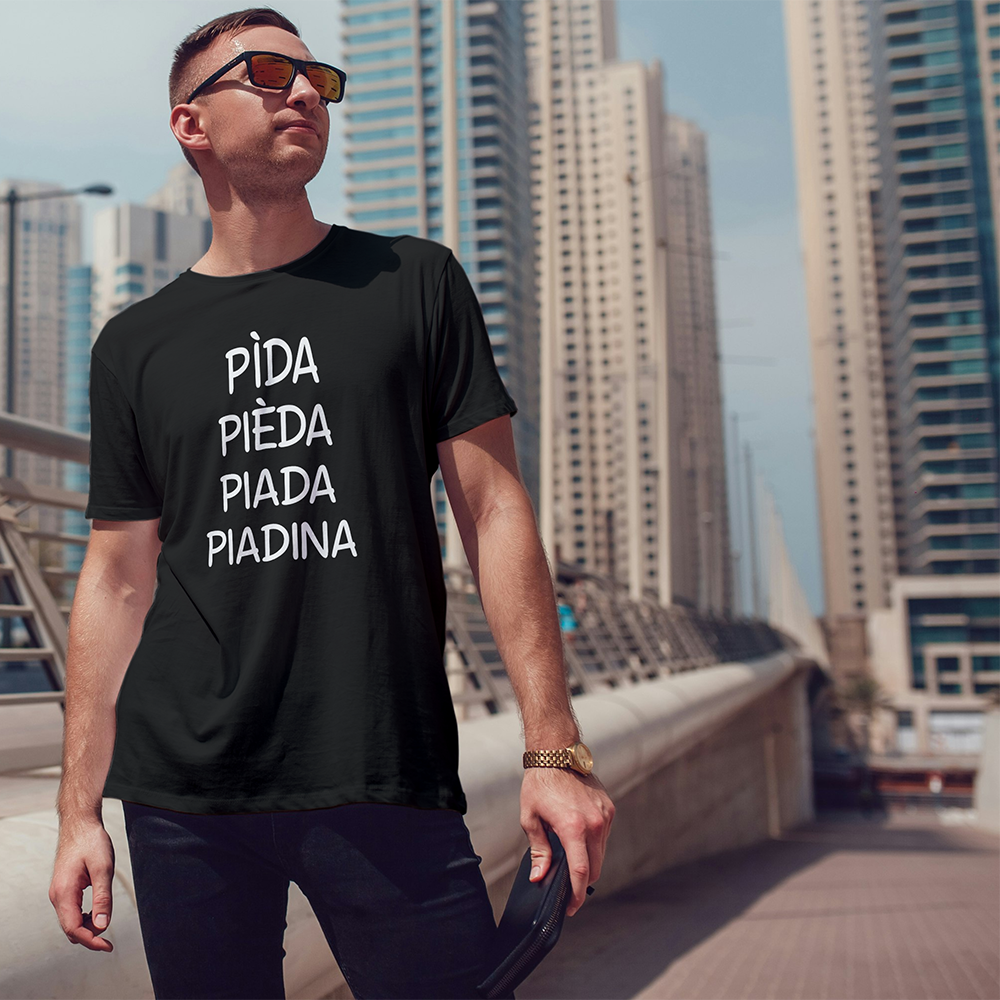Uomo che indossa la T-shirt Piadina de Il mio negozio con testo PiDA PiEDA PiADA PiADINA, in piedi in una città: un'idea regalo originale e un ottimo esempio delle nostre T-shirt personalizzate.