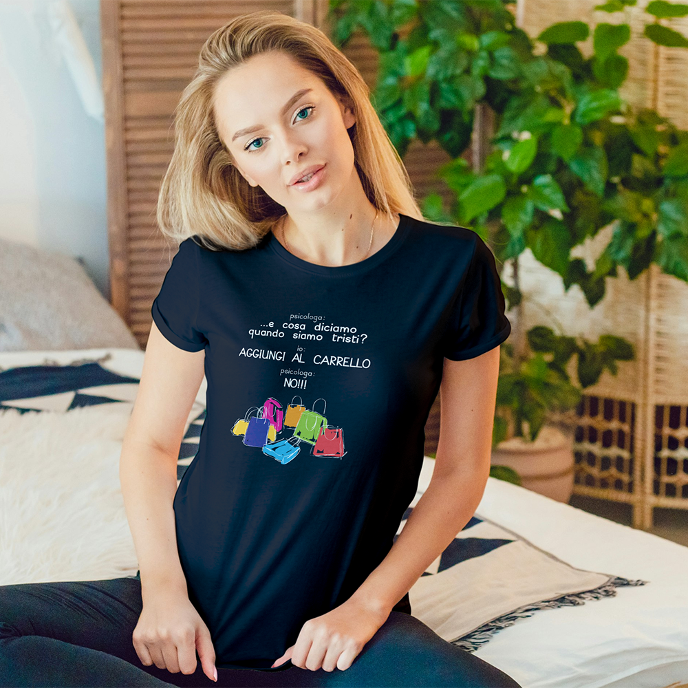 Una donna seduta sul letto indossa la nostra T-shirt Psicologa nera firmata Il mio negozio, circondata da shopping bag colorate con scritte italiane-un regalo originale e perfetto!.