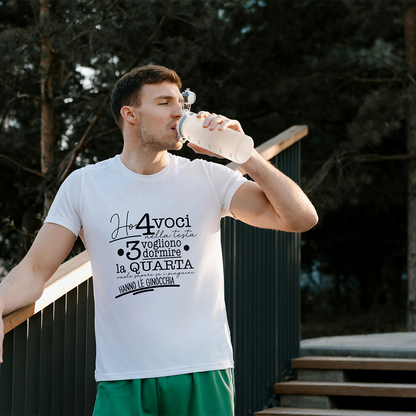 La T-shirt 4 voci de Il mio negozio è appesa a una staccionata di legno. Questa maglietta bianca personalizzata riporta in nero il testo italiano: Ho 4 voci nella testa. 3 vogliono dormire, la quarta vuole sapere se i pinguini hanno le ginocchia.