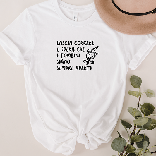 La T-shirt Correre de Il mio negozio è caratterizzata da un testo in italiano e da una figura in corsa dei cartoni animati, con un orlo annodato. Abbinata a un cappello beige e all'eucalipto, è un'idea regalo ideale per gli appassionati di magliette personalizzate divertenti.