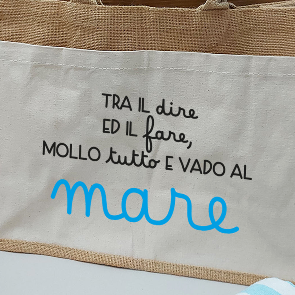 Dettaglio della borsa in juta con tasca frontale in canvas e scritta decorativa sul tema mare.