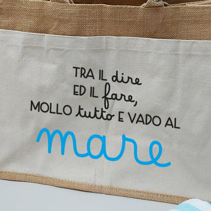 Dettaglio della borsa in juta con tasca frontale in canvas e scritta decorativa sul tema mare.