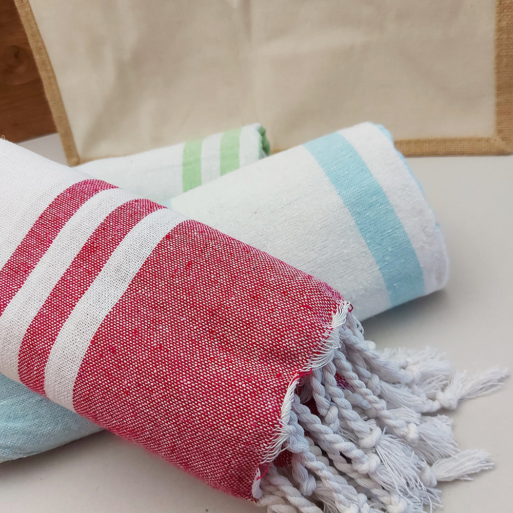 Dettaglio di teli mare fouta arrotolati in diversi colori, con righe bianche e frange decorative.