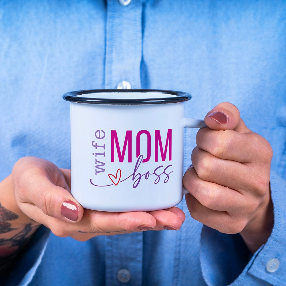 Mug in alluminio dedicata alla mamma con scritta Wife Mom Boss in rosa e lilla, sorretta tra le mani su sfondo azzurro.