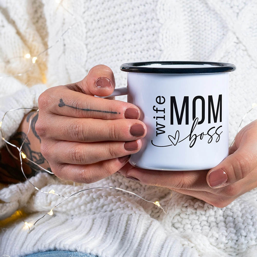 Mug in alluminio dedicata alla mamma con scritta Wife Mom Boss, tenuta tra le mani in un’atmosfera calda e accogliente.