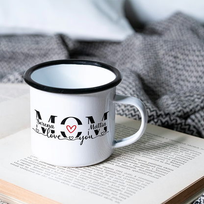 Mug in alluminio personalizzata per la mamma con nomi e dedica, appoggiata su un libro aperto in ambientazione soft.