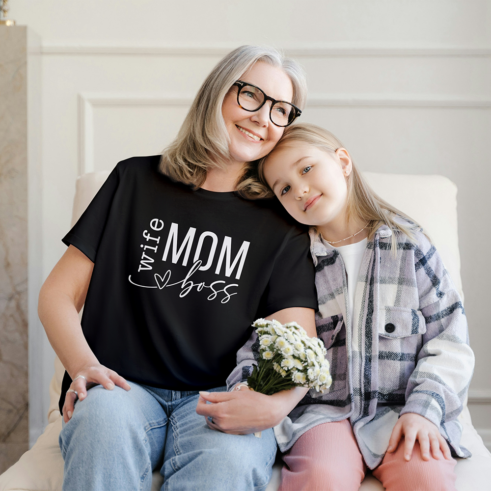 Mamma con t-shirt nera Wife Mom Boss seduta accanto a una bambina, in dolce foto lifestyle dedicata alla Festa della Mamma.