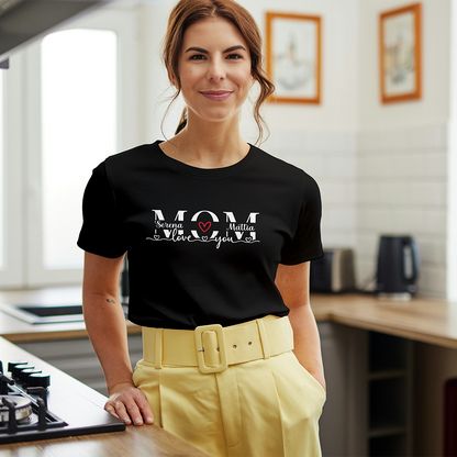 Donna che indossa t-shirt nera personalizzata per la mamma con nomi e dedica, fotografata in cucina.