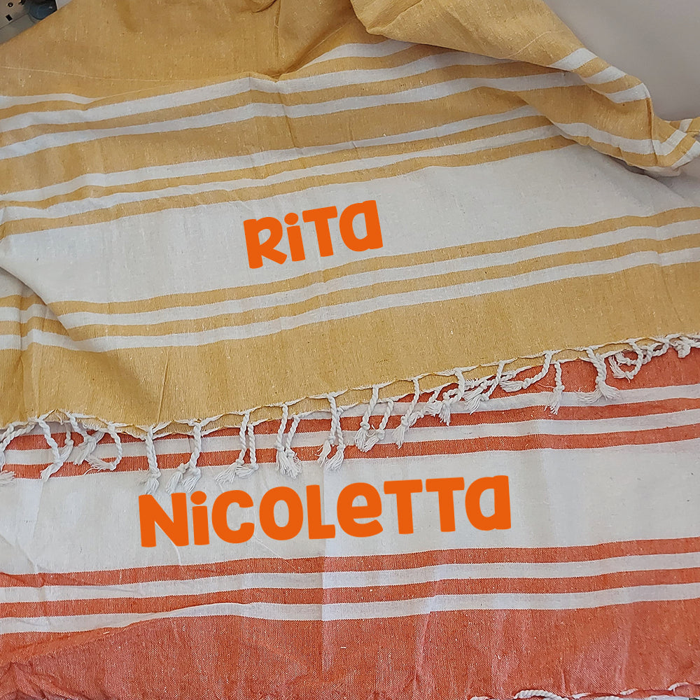 Due teli mare fouta personalizzati nei colori giallo e arancione, con esempio di nome stampato al centro.
