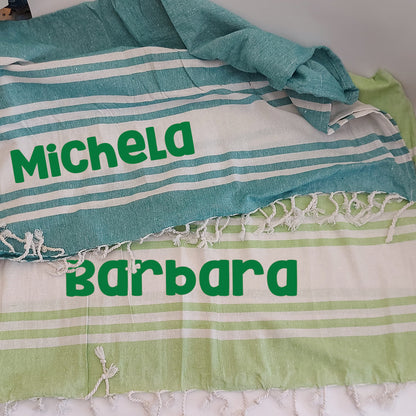 Teli mare fouta personalizzati nei colori verde e verde chiaro, con nomi stampati e dettagli a righe bianche.