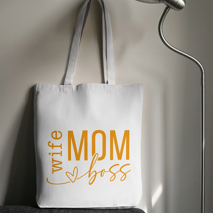 Tote bag bianca dedicata alla mamma con scritta Wife Mom Boss in giallo, fotografata in ambientazione interna.
