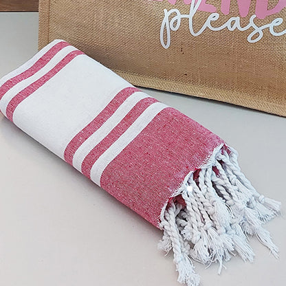 Il Combo Borsa Juta e Telo Fouta WEEKEND di In Casa di Ale è composto da una borsa in juta color tan con la scritta "WEEKEND please" in rosa/bianco e da un asciugamano fouta a righe rosse, ideale per le fughe estive del 2025.