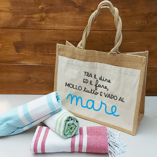 Il Combo Borsa Juta e Telo Fouta MARE di In Casa di Ale è composto da una borsa da spiaggia in juta beige con testo in italiano e tre teli fouta a righe blu, verdi e rosse, ideali per l'estate 2025 al mare.