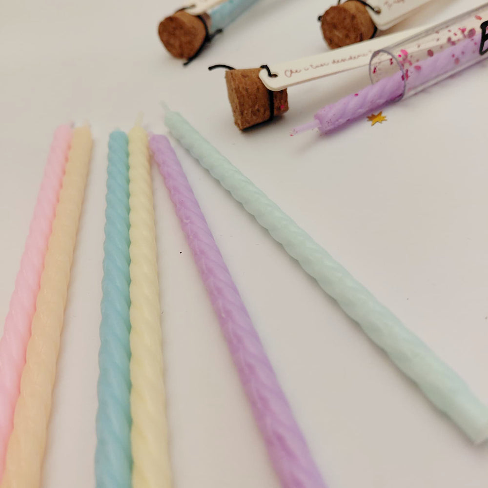 Dettaglio candeline pastello per Ampollina dei Desideri con colori assortiti e ampollina rosa in primo piano