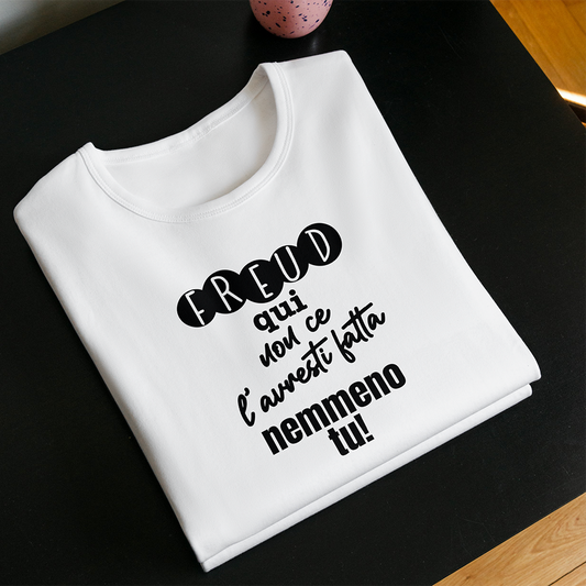 La T-shirt Freud de Il mio negozio è una maglietta bianca ripiegata con il testo italiano "Freud qui non ce l'hai fatta nemmeno tu!" visualizzato su una superficie nera; sullo sfondo compare una tazza rosa con puntini neri, che la rende una perfetta idea regalo.