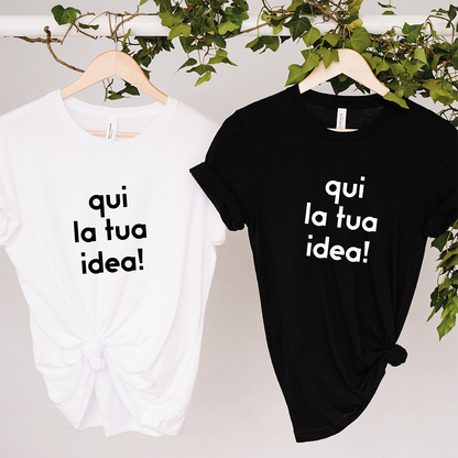 Due "T-shirt da personalizzare" de Il mio negozio sono appese a grucce di legno con sopra un'edera verde. Le magliette bianche e nere mostrano "qui la tua idea!"-perfette come magliette personalizzate divertenti o idee regalo originali.