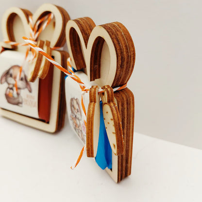 Vista laterale del porta cioccolatino di Pasqua in legno che mostra la struttura a tre strati e le carotine decorative