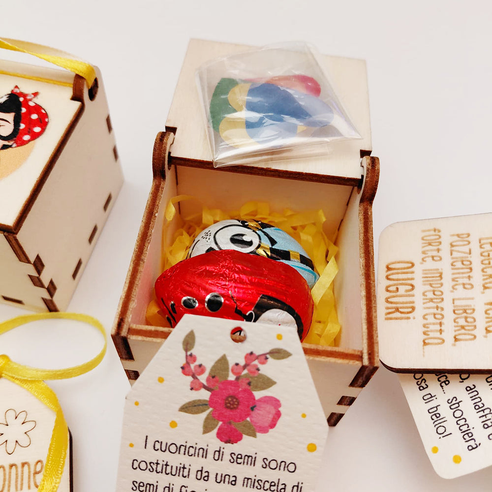 Interno scatolina in legno con paglia gialla, cioccolatini ape e coccinella e cuoricini piantabili con semini