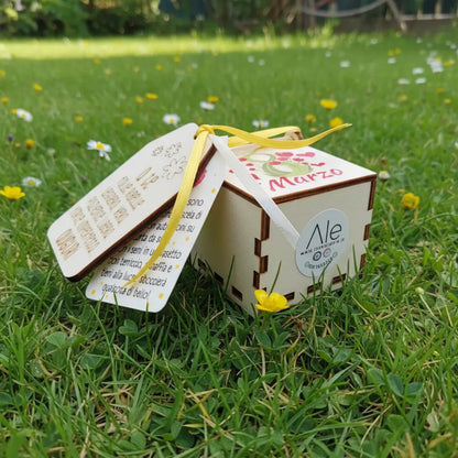 Scatolina in legno 5x5 per Festa della Donna con coperchio decorato, tag con dedica e nastri gialli, foto su prato