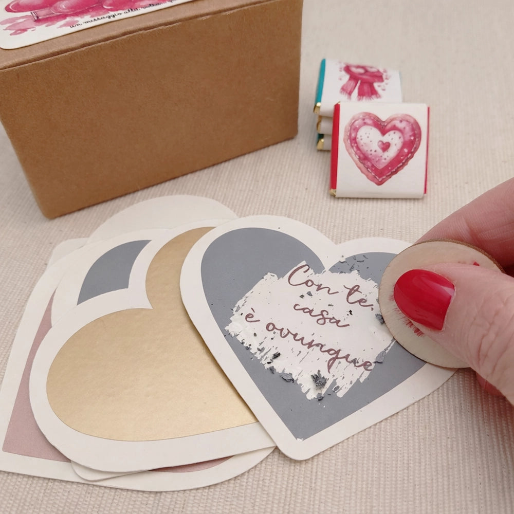 Mano che gratta un cuore con monetina in legno, frase che si scopre sotto il gratta e vinci