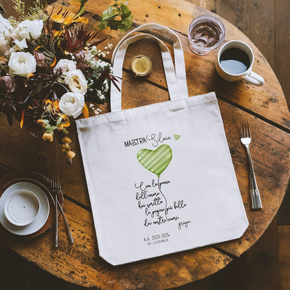 Tote bag maestra personalizzata con cuore verde e poesia, shopper in cotone appoggiata su tavolo