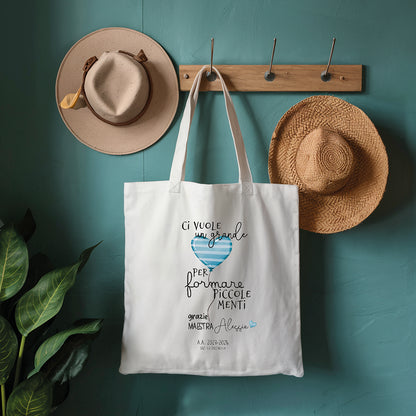 Tote bag maestra personalizzata con frase piccole menti e cuore azzurro, shopper in cotone su parete azzurra