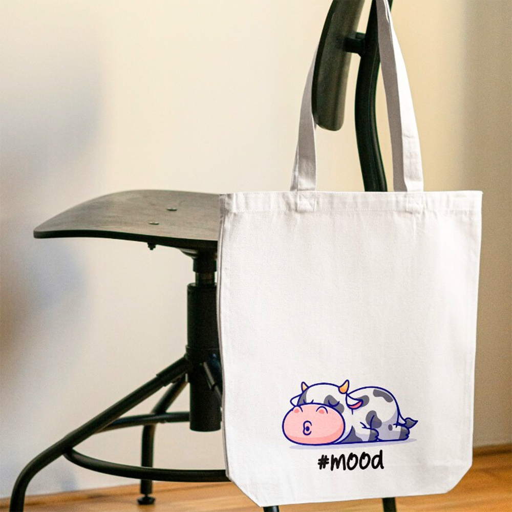 Tote bag mood con mucca lilla addormentata, shopper in cotone bianca appesa a una sedia
