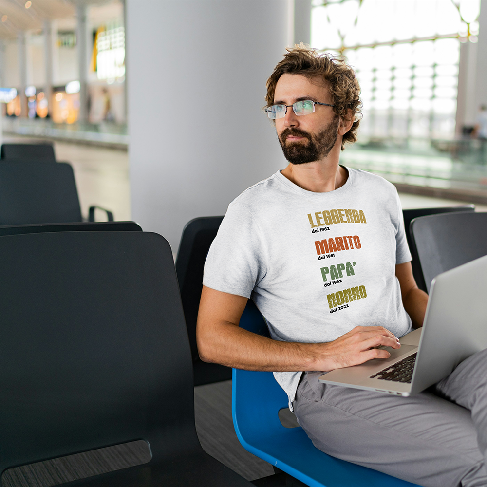 Uomo seduto con t-shirt bianca “Leggenda, Marito, Papà, Nonno” e anni personalizzabili