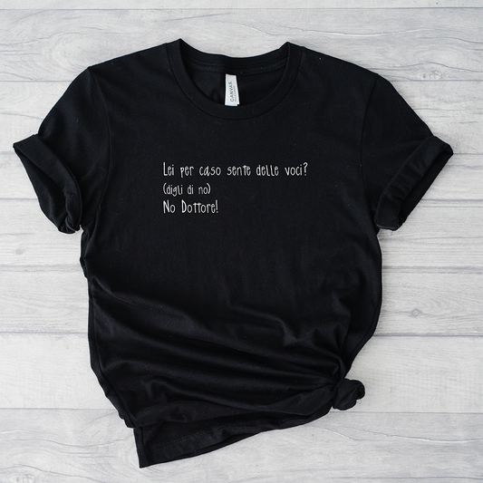 Il mio negozio T-shirt Sento voci nere con la scritta italiana "Lei per caso sente delle voci? (dica di no) No Dottore!" su sfondo in legno chiaro.